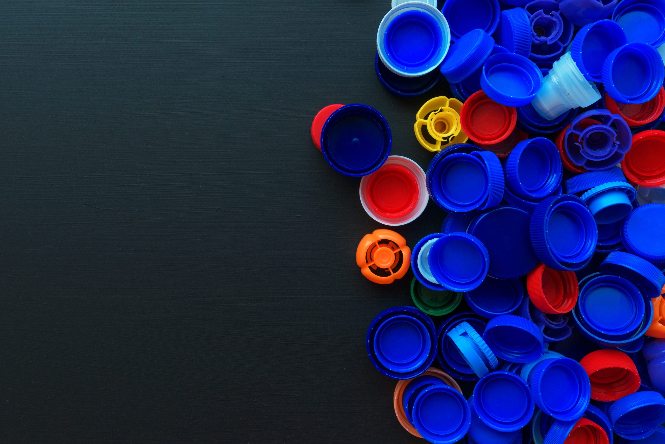 Recycled plastic bottle caps in various colors, top view